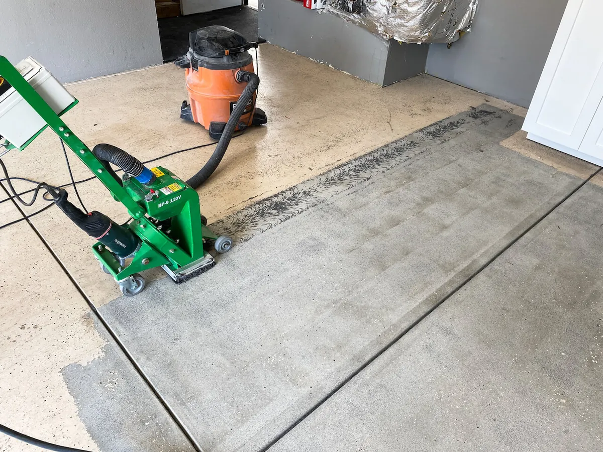 Old coating being ground off a garage floor slab with a walk-behind grinder
