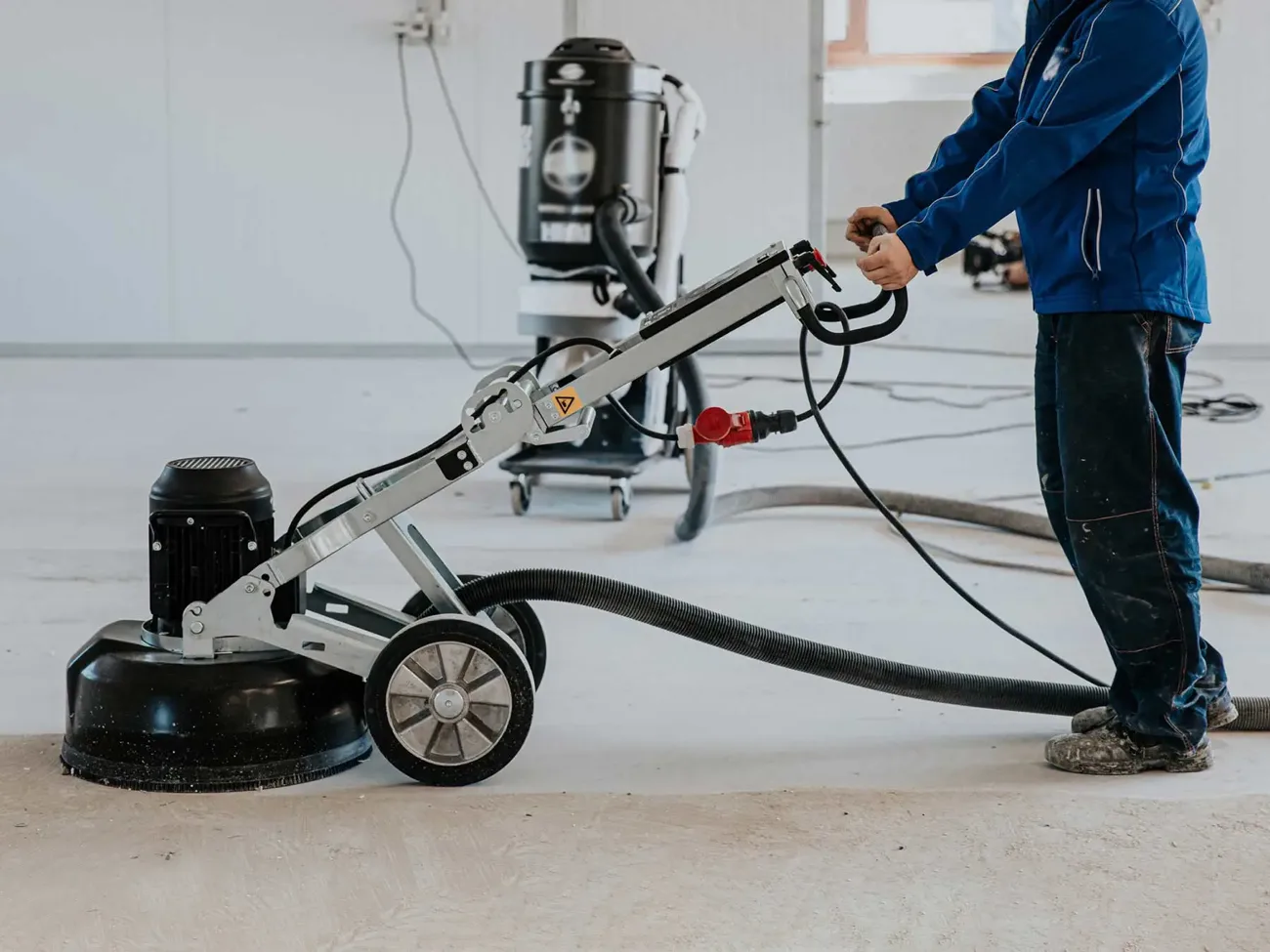 Concrete floor grinder with dust extraction preparing a slab