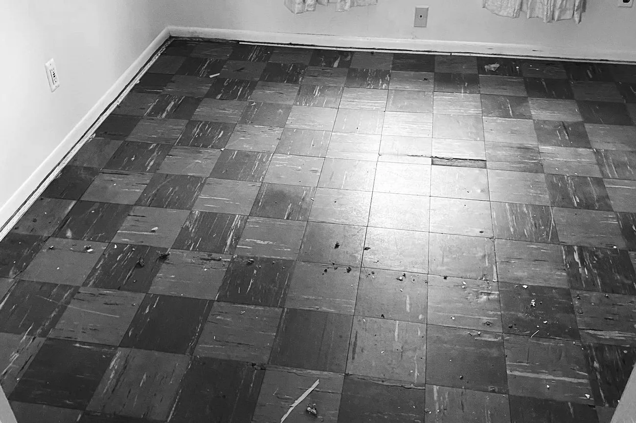 Old 9 by 9 inch vinyl floor tiles in an empty room, the kind of floor that gets tested before a tear-out